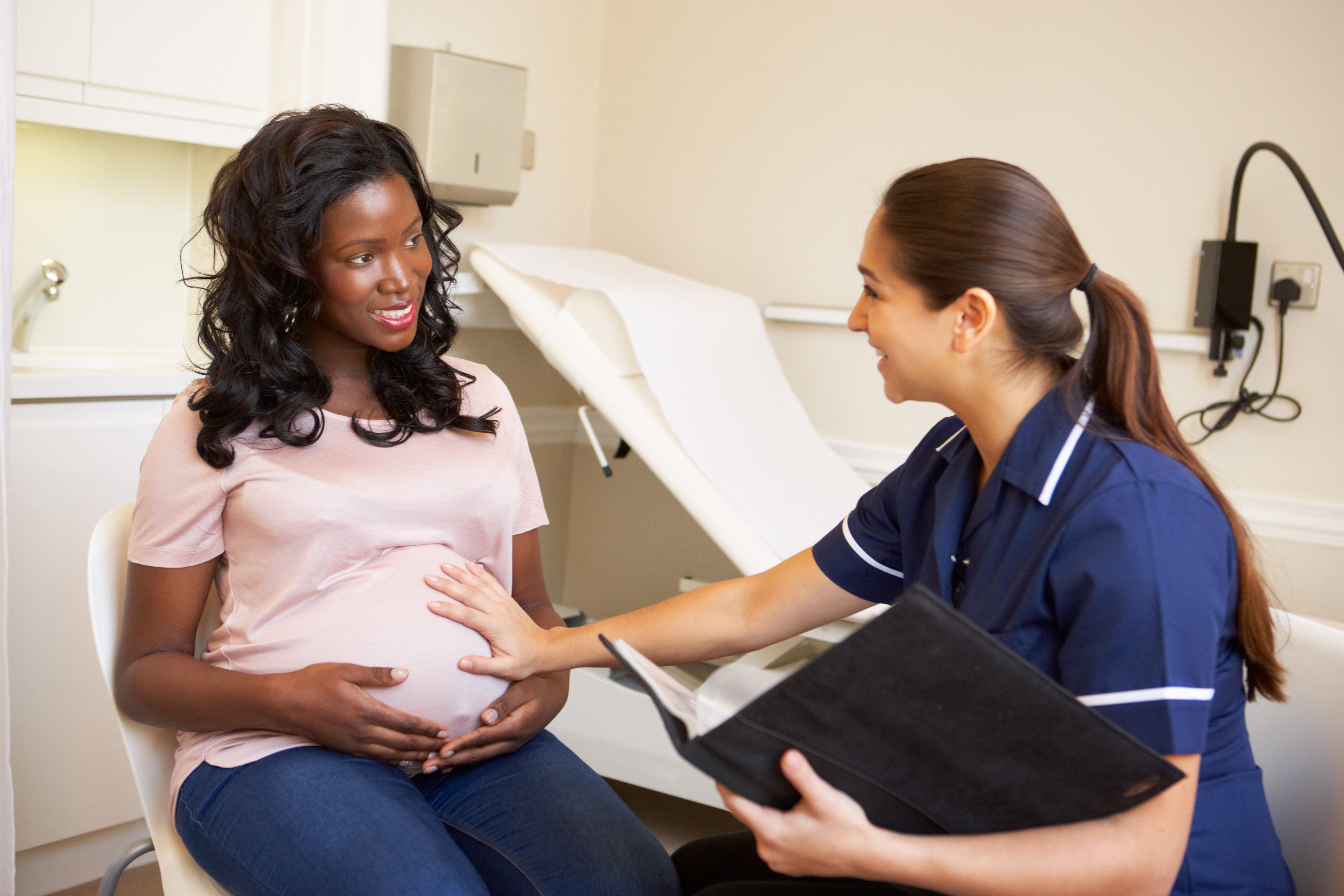 A pregnant woman speaking to a nurse about her pregnancy